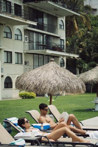 two people laying in lawn chairs under an umbrella at Hotel Master Club in Tequesquitengo
