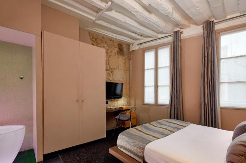 a bedroom with a bed and a desk and a television at H&ocirc;tel de Notre-Dame in Paris
