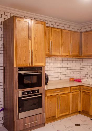 a kitchen with wooden cabinets and an oven at The Noble Villa, Ikorodu, Lagos in Ikorodu