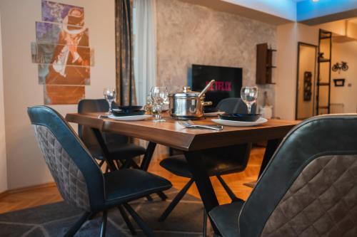 a wooden table with chairs and wine glasses on it at - All-Around Skopje Apartments - Premium Hospitality - in Skopje