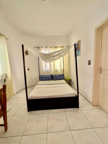 a bed with a canopy in a room at Guesthouse Cocotiers Cotonou in Cotonou