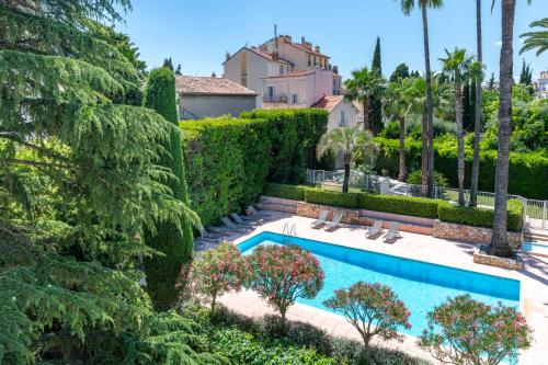 - une piscine dans une cour arborée et un bâtiment dans l'établissement Superbe Appartement avec Piscine et Toit Terrasse, à Cannes