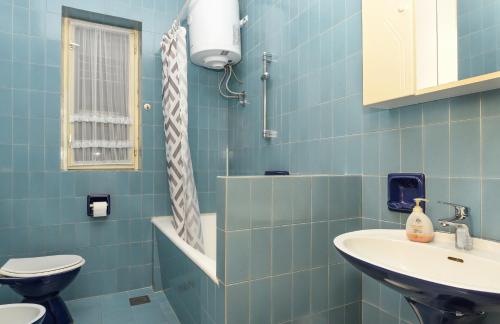 a blue tiled bathroom with a toilet and a sink at App Jadranka Matak in Rabac