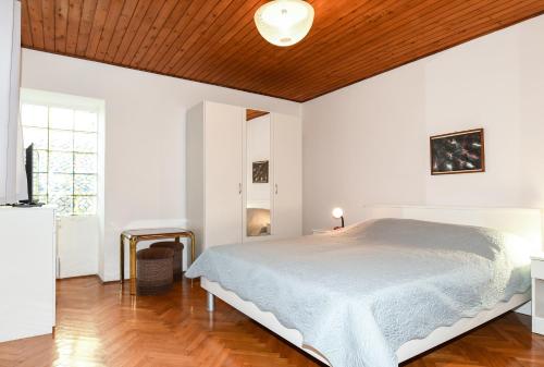a white bedroom with a bed and a wooden ceiling at App Jadranka Matak in Rabac