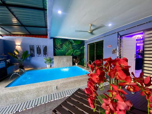 a swimming pool in a living room with red flowers at Ilham Restu Homestay Private Pool MSLIM ONLY in Port Dickson