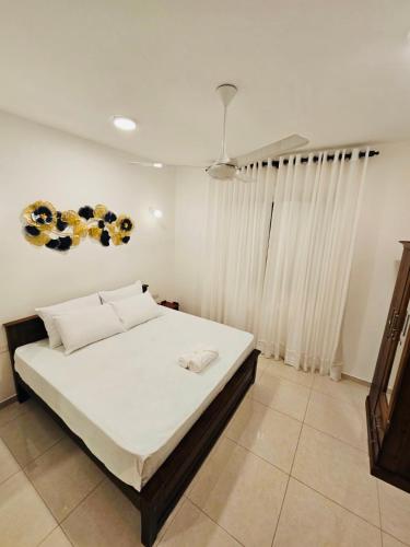 a bedroom with a bed with white sheets and curtains at Secret Passage in Uswetakeiyawa