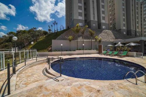 una piscina in un hotel con sedie e un edificio di Apto Novo Próx Shopping Poços MG a Poços de Caldas