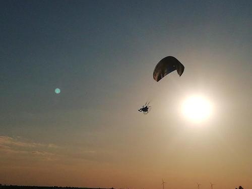 a person flying a parachute in the sky at Przystanek Las in Gąsawa