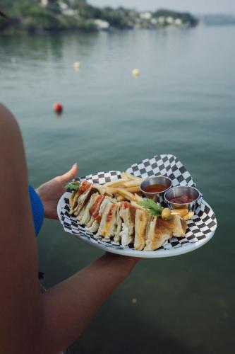 a person holding a plate with a sandwich and french fries at Hotel Master Club in Tequesquitengo