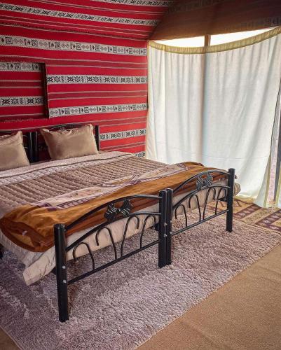 Bedouin guide camp في وادي رم: سرير في غرفة ذات جدار أحمر