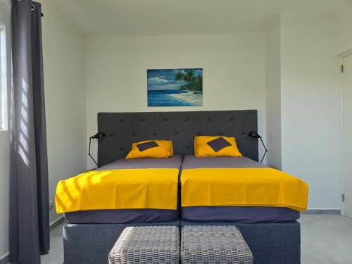 a bed with a yellow blanket and two yellow pillows at La Cesarina in Willemstad