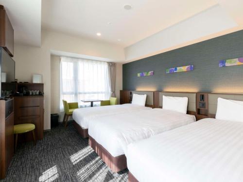 a hotel room with two beds and a desk at Comfort Hotel ERA Kyoto Toji in Kyoto