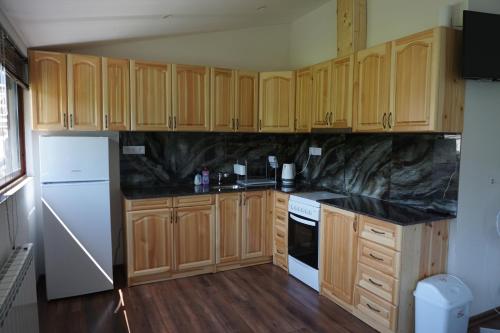 a kitchen with wooden cabinets and black counter tops at Guesthouse Juli in Sapareva Banya