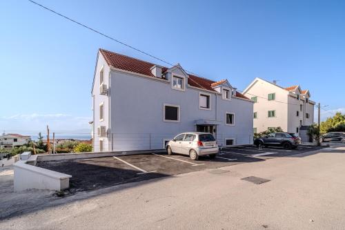 a white building with a car parked in a parking lot at Apartmani Indigo in Supetar