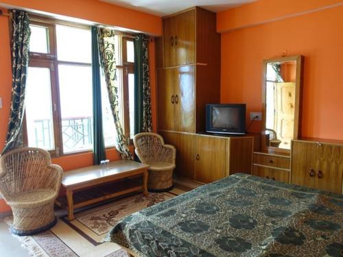 1 dormitorio con paredes de color naranja, 1 cama y TV en Malis Apple Lodge, en Nagar
