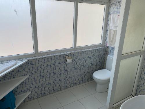 a bathroom with a toilet and three windows at Hôtel Petite Suède in Agadir