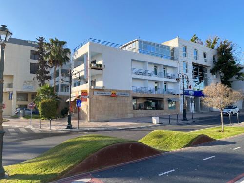 a building on a street with a grassy hill in front at H&ocirc;tel Petite Su&egrave;de in Agadir