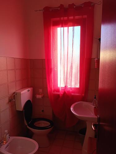 a red bathroom with a toilet and a sink at Grazioso bilocale in Giusvalla