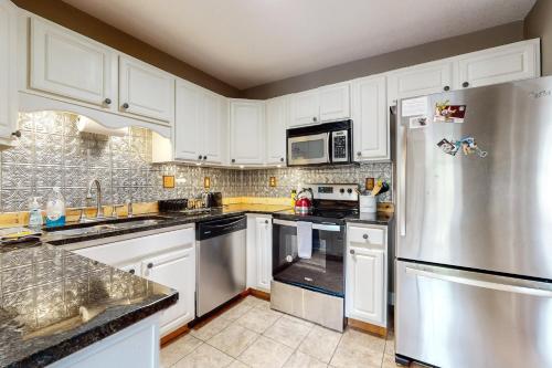 a kitchen with white cabinets and a stainless steel refrigerator at Acorn House in Fletcher