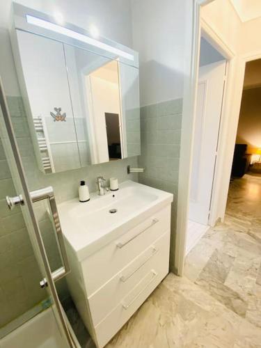 une salle de bain avec un lavabo blanc et un miroir dans l'établissement Les nereides bord de mer calme lumineux parking, à Roquebrune-Cap-Martin