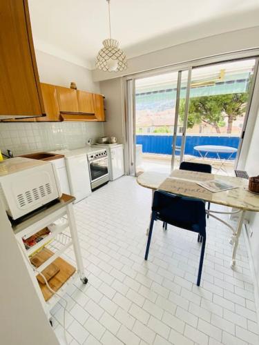 une cuisine avec une table et une vue sur l'océan dans l'établissement Les nereides bord de mer calme lumineux parking, à Roquebrune-Cap-Martin