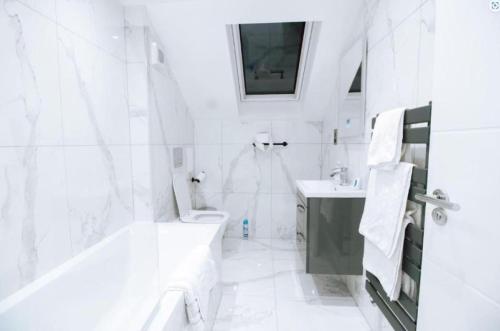 a white bathroom with a tub and a toilet and a sink at Purley 2 Bed Flat in Purley