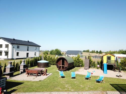 - un ensemble de chaises assises dans une cour avec une aire de jeux dans l'établissement U Adama i Ewy, à Gąski