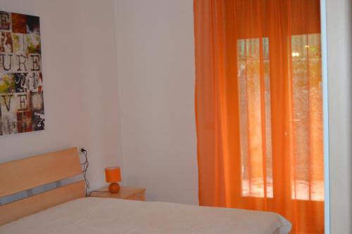 a bedroom with a bed and an orange curtain at Haus and Beach in Brenzone sul Garda