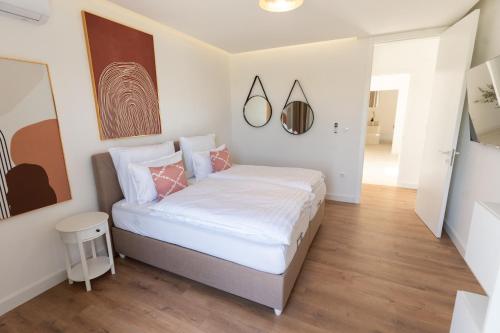 a bedroom with a bed with white sheets and pink pillows at Villa Bellevue in Mostar