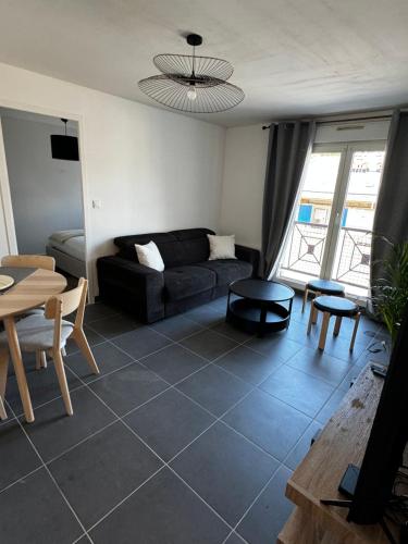 un salon avec un canapé noir et une table dans l'établissement Au cœur de Port, à Port-en-Bessin-Huppain