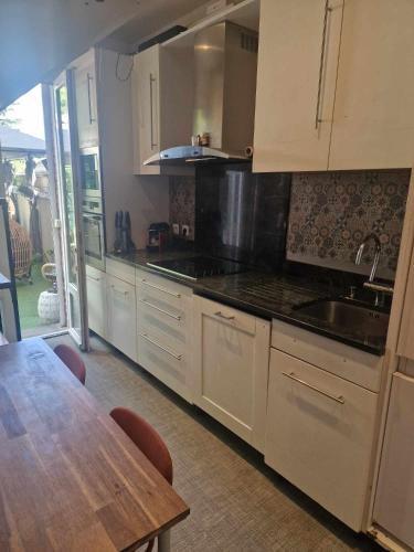 une cuisine avec des armoires blanches et une table en bois dans l'établissement Le jasmin, à Aulnay-sous-Bois