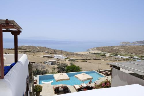a view of a swimming pool with umbrellas and the ocean at VILLA NAUTILIA - Luxury Suites and Cottages in Kalafatis