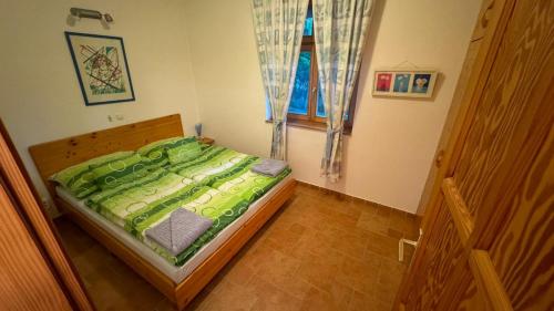 a bedroom with a green bed with a window at Reichelhausen Vendégház in Kiskunhalas