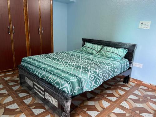 a bed with a green comforter in a room at Dwaraka Home Stay in Tirupati