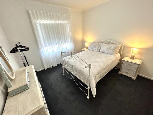 a bedroom with a bed and two lamps and a window at Casa De Praia - Entire Home - North Beach in Wallaroo