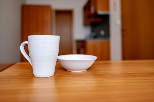 a white cup and a bowl on a wooden table at Relax Hotel Stork in Lednice