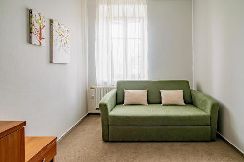 a green couch in a room with a window at Relax Hotel Stork in Lednice