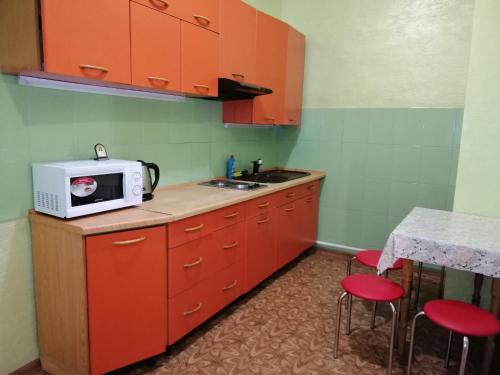 a kitchen with orange cabinets and a microwave on a counter at Apartamenty u Deribasovskoi in Odesa