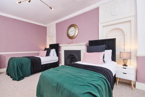 two beds in a room with a clock on the wall at Beautiful 2 Bedroom 3 actual beds House with WiFi by PureStay in Bath