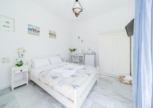 a white bedroom with a bed and a table at Agia Anna Living in Agia Anna Naxos