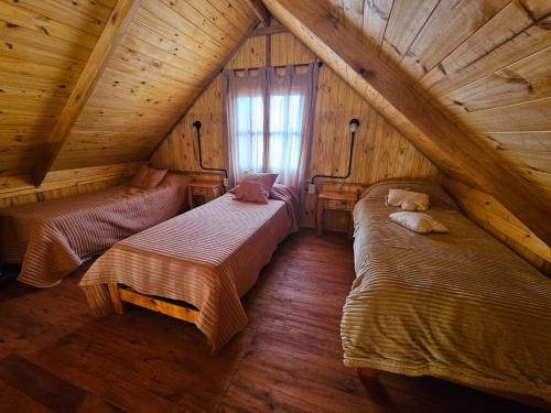 une chambre mansardée avec deux lits et une fenêtre dans l'établissement Cabañas en Los Reartes Córdoba, à Villa General Belgrano
