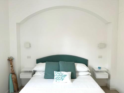 a white bed with a green headboard and white pillows at Starhost - CASA BONNIE, large furnished balcony on the Cathedral and a stone's throw from seafront, beach and ferry's pier in Minori