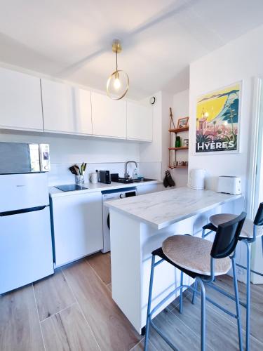 une cuisine avec des armoires blanches et une table et des chaises dans l'établissement Le Repaire des Palmiers - T2 en centre-ville avec parking et piscine, à Hyères