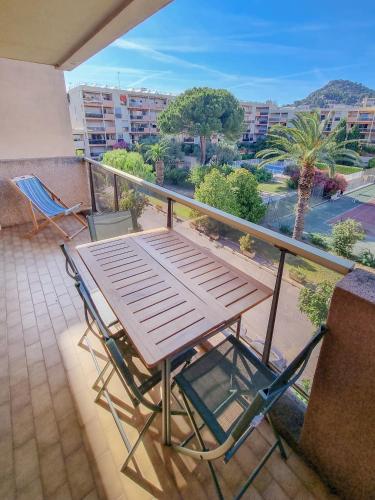 une table en bois et deux chaises sur un balcon dans l'établissement Le Repaire des Palmiers - T2 en centre-ville avec parking et piscine, à Hyères