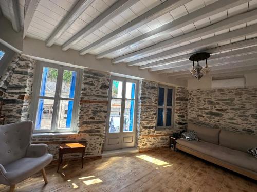 a living room with a couch and some windows at Plomari Nomad House in Plomarion