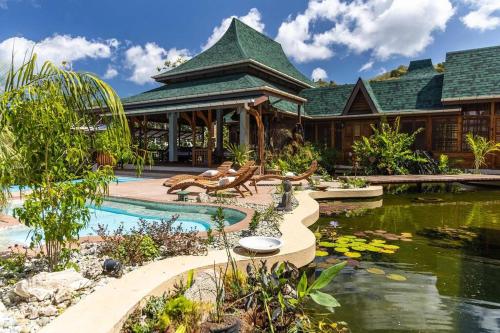 a house with a pond in front of a building at Ohana Villa, Tobago in Scarborough