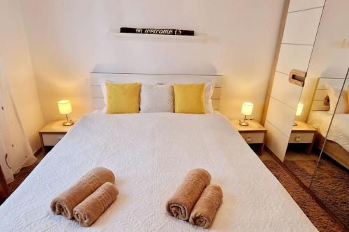 a bedroom with a large white bed with two brown towels at FLH - Garden Grill Escape in Sibiu