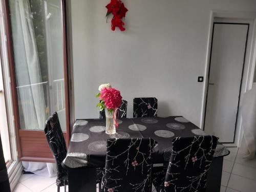 une table de salle à manger avec un vase de fleurs dessus dans l'établissement chez wioletta et pascal, à Athis-Mons