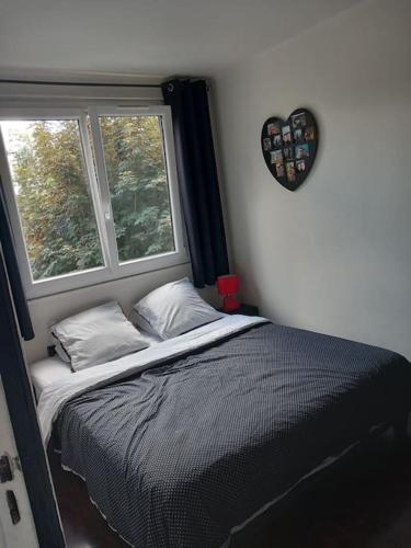 - une chambre avec un lit et une fenêtre avec un cœur sur le mur dans l'établissement chez wioletta et pascal, à Athis-Mons