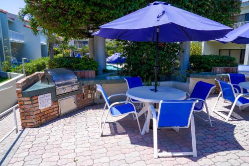 a table and chairs with an umbrella and a grill at Ventura at Boca Raton in Boca Raton